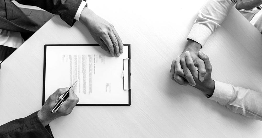 Manos de dos hombres de negocios sobre una mesa uno de ellos a punto de firmar un contrato.